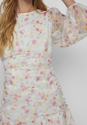 Blumenkleid mit weißem Hintergrund und pinken, gelben und lila Blumen. Puffärmel und geraffte Details verleihen Textur.