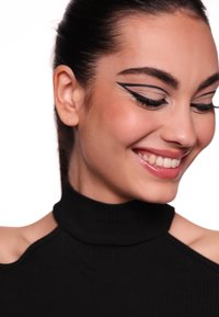 Top nero a collo alto con texture a coste. Il modello presenta un eyeliner grafico audace, pelle liscia e un leggero sorriso su uno sfondo bianco.