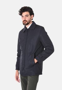 Giacca nera, leggera e imbottita, con colletto a punta, chiusura frontale con zip e tasche laterali. Presenta una finitura liscia e una vestibilità comoda.