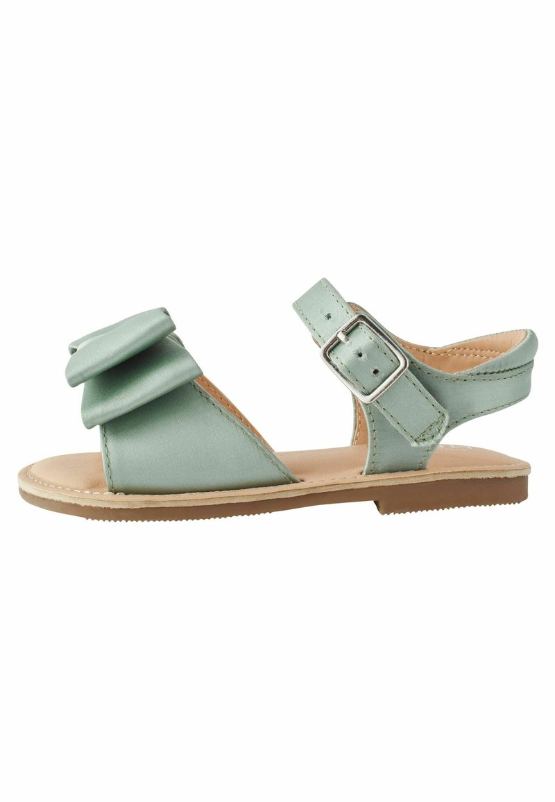 Lysegrøn flad sandal med åben tå, ankelrem med sølvspænde og lagdelt sløjfedetalje på den forreste rem.