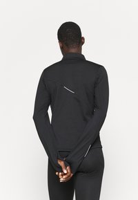 Schwarzes langärmliges Sportoberteil mit hohem Kragen, schlankem Design und reflektierenden Akzenten entlang der Schulternaht, aus dehnbarem Stoff gefertigt.