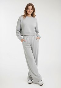 Felpa corta grigio chiaro con maniche lunghe e pantaloni abbinati a vita alta e gamba larga. Entrambi i capi hanno una finitura texturizzata.
