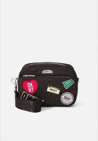 Fekete nejlon keresztpántos táska több folttal, ezüst színű fémrészekkel, cipzáras záródással és a DKNY logóját viselő fonott pánttal.