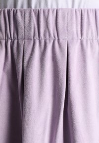 Lila kjol med elastisk midja, texturerad tyg, veckad design, slät yta och mjukt utseende, lämplig för avslappnad användning.