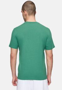 T-shirt verde a maniche corte in cotone, con colletto a girocollo e una superficie liscia, con dettagli delle cuciture sulle maniche e sull'orlo.