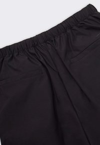 Pantaloni neri con vita elasticizzata, in tessuto leggero, dotati di due tasche posteriori con bordi cuciti, texture liscia e vestibilità rilassata.