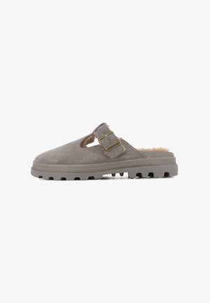 Sandale à semelle glissante en suède gris avec un bout arrondi, des côtés découpés, une doublure en fourrure et un accent en boucle dorée sur la sangle. Semelle en caoutchouc texturé.