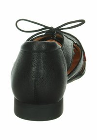 Chaussure en cuir noir avec un talon arrondi, détails de lacets à l'arrière et design découpé sur les côtés exposant un intérieur beige. Texture lisse.