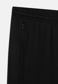 Pantalones deportivos negros con una textura suave, con una cintura elástica y un bolsillo lateral con cremallera. Detalles de panel de malla a lo largo de los lados.