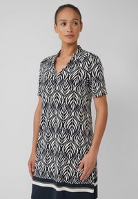 Kurzarmkleid mit einem Navy- und Creme-Blattmuster, V-Ausschnitt und einem horizontalen Creme-Streifen am Saum. Glatte Stoffoberfläche.