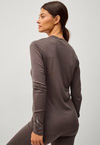Bruine lange mouwen shirt gemaakt van zacht materiaal, met een ronde halslijn en een aansluitend ontwerp met een logo-opdruk op de mouw.