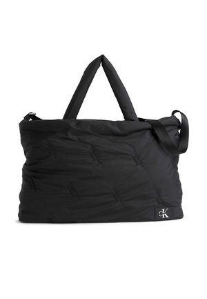 Black padded duffel bag with top handles, adjustable shoulder strap, and small Calvin Klein logo patch in bottom corner.