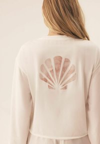 White sweatshirt featuring a large shell graphic on the back, made of soft fabric with a relaxed fit and round neckline.