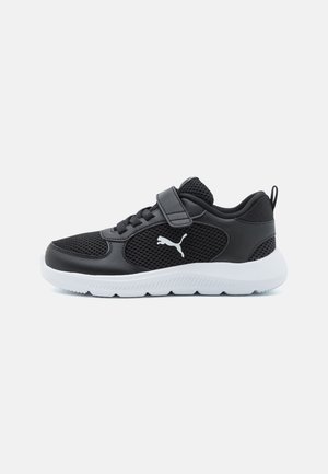 Baskets de sport noires avec une tige en mesh, une sangle Velcro, des lacets et une semelle en caoutchouc blanche. Présente le logo Puma en blanc sur le côté.