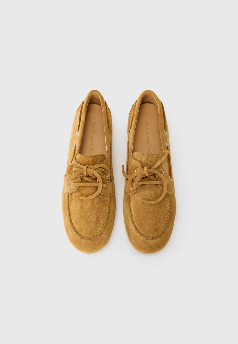Braune Wildlederbootsschuhe mit runder Zehenpartie und Schnürdesign, ausgestattet mit silbernen Ösen und sichtbaren Nähdetails im Obermaterial.
