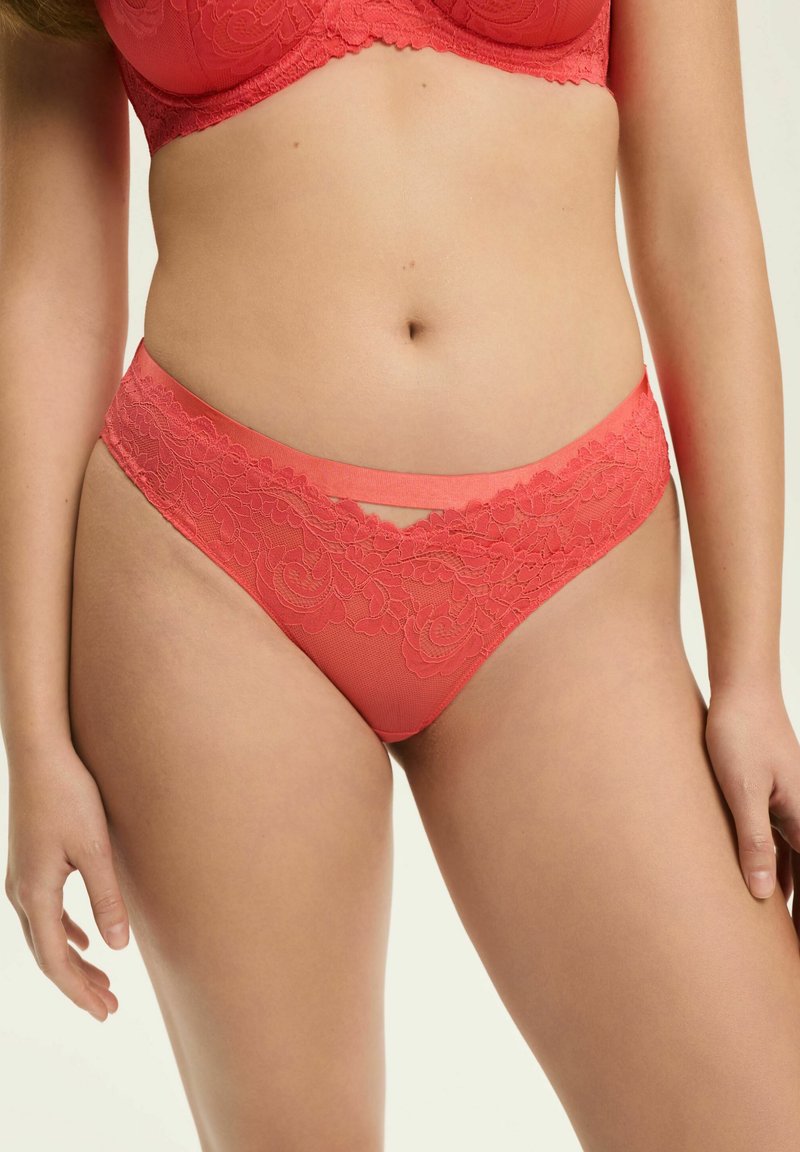 Koronkowe majtki w kolorze koralowym z kwiatowym wzorem i satynowym pasem, charakteryzujące się miękkim siateczkowym materiałem i wycięciem z przodu.