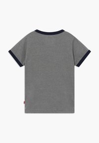 Camiseta gris de manga corta con cuello y puños en color navy, vista desde atrás sobre un fondo blanco.