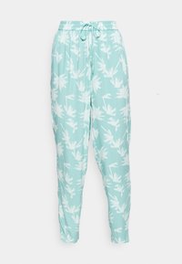 Ljus turkosa byxor med vitt palmträdsprint, elastisk midja och dragsko fram, visade på en neutral vit bakgrund.