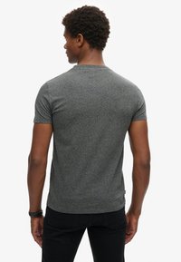 Gray short-sleeve t-shirt with a textured fabric; features a crew neck and a fitted style, worn with black pants.