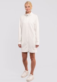Abito bianco con zip, collo alto, maniche lunghe e orlo con coulisse. Realizzato in un tessuto morbido, presenta un design minimalista e hardware discreto.