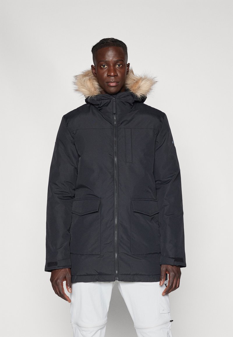 Μαύρο παρκά μπουφάν με επένδυση από συνθετική γούνα στην κουκούλα, φερμουάρ μπροστά και δύο μπροστινές τσέπες. Διαθέτει ματ φινίρισμα και ρυθμιζόμενους καρπούς.