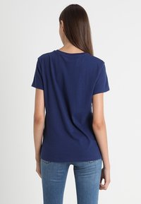 Marineblaue Kurzarm-T-Shirt mit Rundhalsausschnitt und lässiger Passform, aus weichem Baumwollstoff gefertigt, mit einer glatten Textur.
