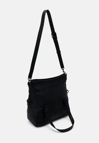 Czarna torebka na ramię z teksturowanego materiału, regulowanym paskiem i ozdobami w postaci klamerek. Płaski, prostokątny kształt z zamkiem błyskawicznym na górze.