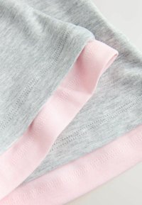 Gros plan sur un tissu plié montrant du coton côtelé doux gris et rose clair avec des détails de couture visibles.