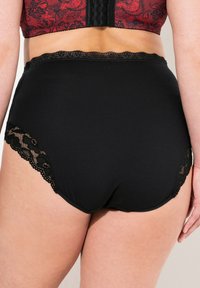 Slip neri a vita alta realizzati in tessuto morbido con pizzo lungo il bordo della vita e delle aperture delle gambe, caratterizzati da motivi floreali lungo i bordi.