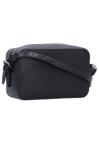 Borsa cosmetica nera con superficie strutturata, forma rettangolare, chiusura con zip e tracolla regolabile per il trasporto.
