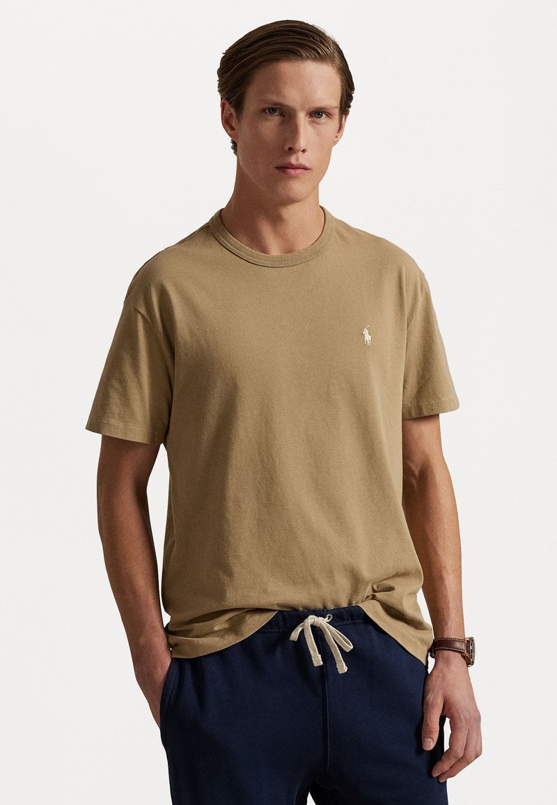 Tan bomulls t-shirt med rund hals och korta ärmar, med en liten broderad logotyp på bröstet, ihop med marinblå sweatpants med dragsko.