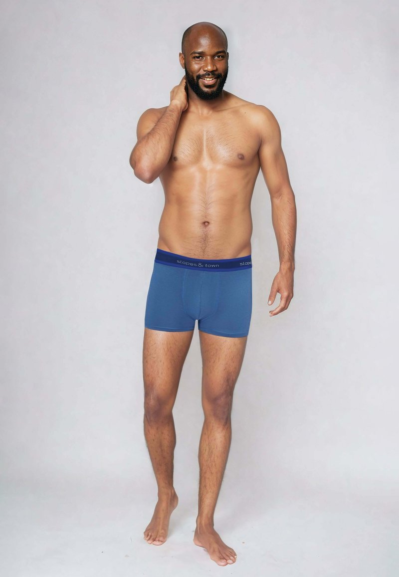 Niebieskie majtki z kontrastowym ciemnym pasem z brandingiem "slopes & town". Miękka tkanina, dopasowany krój i długość do połowy uda.