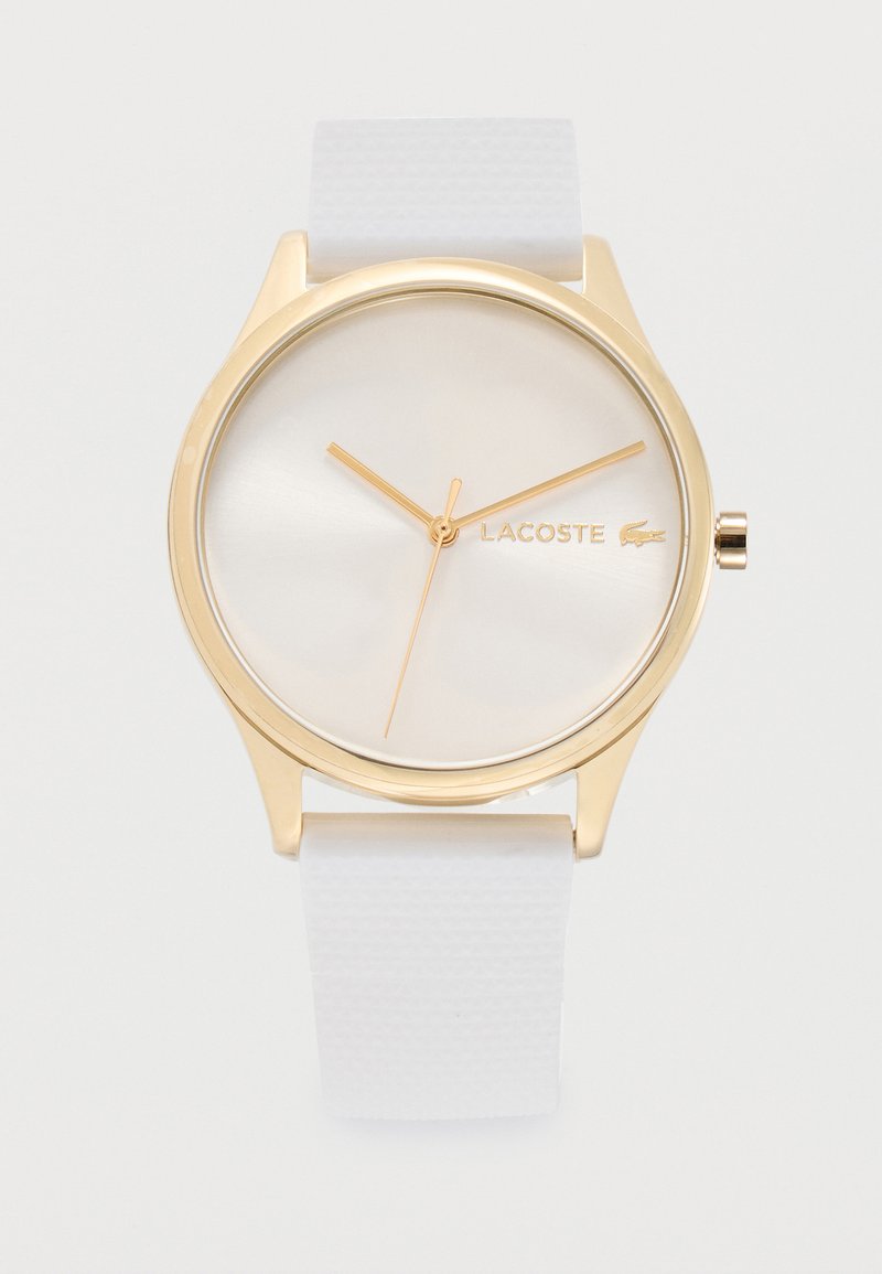 Zegarek na rękę Lacoste w złotym odcieniu, z okrągłą białą tarczą, minimalistycznymi złotymi wskazówkami, logo oraz teksturowanym białym silikonowym paskiem.