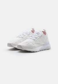 Zapatillas deportivas blancas con un upper texturizado, paneles de malla, cordones y una suela gruesa y acolchada. Presentan sutiles acentos en rosa en la leng�üeta.