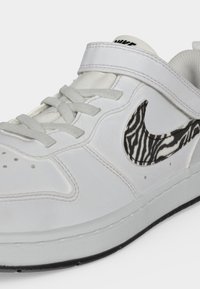 Λευκό αθλητικό παπούτσι Nike με γκρι κορδόνια, ιμάντα με στερεωτικό και ασπρόμαυρο σχέδιο ζέβρας στο λογότυπο Nike swoosh.