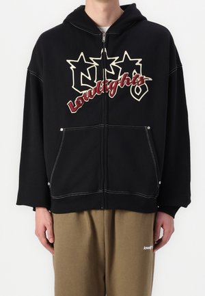 Black zip-up hoodie featuring a large graphic text design in cream and burgundy, with front pockets and contrasting white stitching.