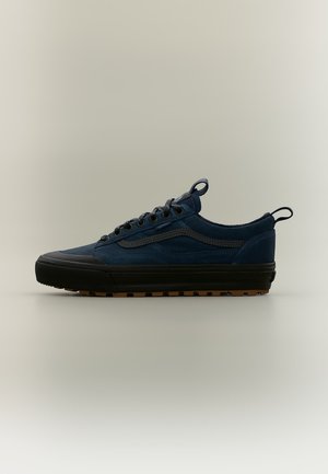 Zapatilla baja azul marino con suela negra, cordones delanteros y lengüetas en la lengüeta y el talón, mostrada de perfil sobre un fondo claro.