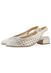 Zapatos slingback plateados con un acabado metálico texturizado, que presentan un diseño con cortes y un tacón bajo tipo bloque. Suela plana y punta cerrada.
