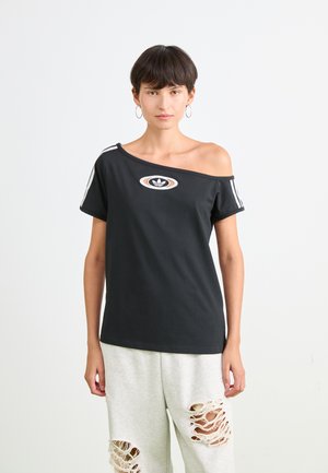Schwarzes Off-Shoulder-T-Shirt mit einem orange und weißen Logo, kurzen Ärmeln mit weißen Streifen, kombiniert mit grauen, zerrissenen Sweatpants.