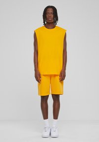 Gul ærmeløs top og matchende shorts, lavet af blødt stof. Har en afslappet pasform, crew neckline og shorts der går til midt på låret.