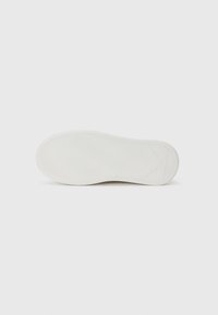 White sneaker sole with textured grooves and a clear tread pattern, featuring a distinct angled design at the heel and midsole.