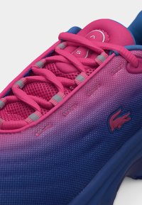 Baskets dégradé rose et bleu avec lacets roses, languette en mesh et petit logo crocodile sur le panneau latéral.