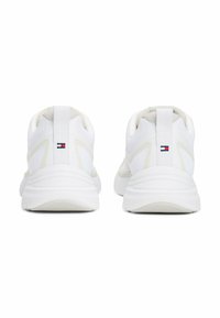 Scarpe da ginnastica bianche con tomaia in rete e suola in gomma; presentano una superficie testurizzata e un piccolo logo blu, rosso e bianco sul tallone.