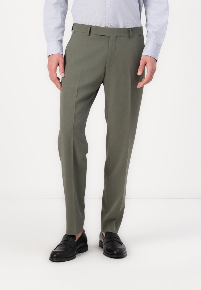 Olivgröna byxor i slät tyg, med skräddarsydd passform, pressveck fram och bälteshällor, ihop med svarta läderslip-in skor.