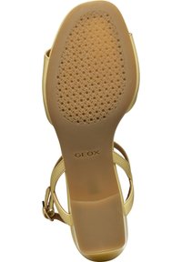 Sandalias de tacón alto en color beige con correas de cuero y una suela de goma con patrón. Presenta una puntera redondeada y una hebilla en el tobillo para un ajuste seguro. Marca Geox visible.