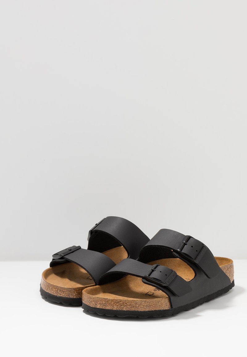 Black sandals featuring two adjustable straps, cork footbed, and textured rubber outsole for grip. Simple design with a classic profile.