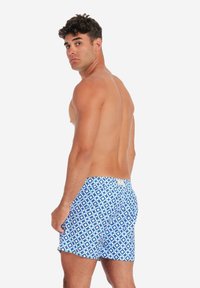 Blaue Badehosen mit geometrischen Mustern, aus leichtem Material gefertigt, verfügen über einen elastischen Bund und eine weiche Textur.