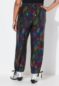 Pantalones de lentejuelas multicolores con un corte relajado, que cuentan con un dobladillo ajustable y una textura brillante, mostrando un patrón abstracto vibrante.