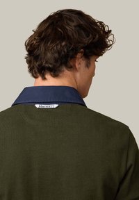 Ciemnozielony sweter dziany z granatowym kołnierzem. Metka z tyłu z napisem "Hackett." Tkanina o fakturze, dopasowany fason.