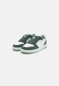 Green and white sneakers with a textured suede upper, perforated toe, and rubber sole. Features rounded laces and branded accents.